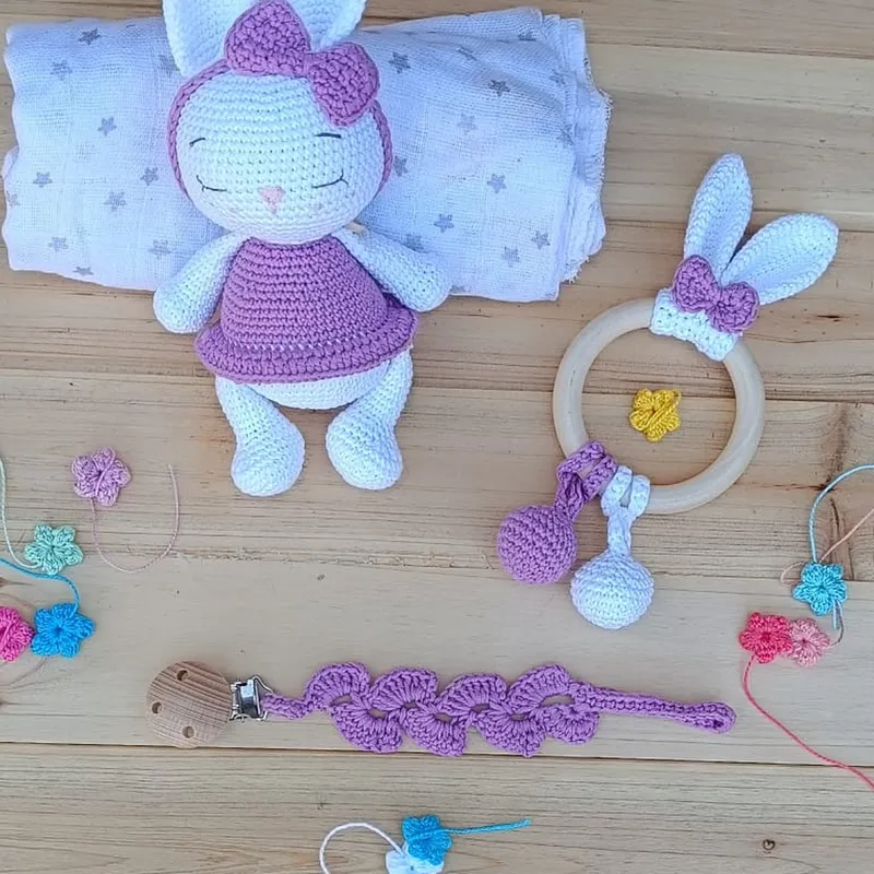 Vista general del set artesanal de crochet Conejilda para bebé, mostrando la conejita de apego, el sonajero y el chupetero coordinados sobre fondo neutro